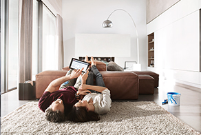 Man and woman lying on the floor looking at their ipad with the free@home software
